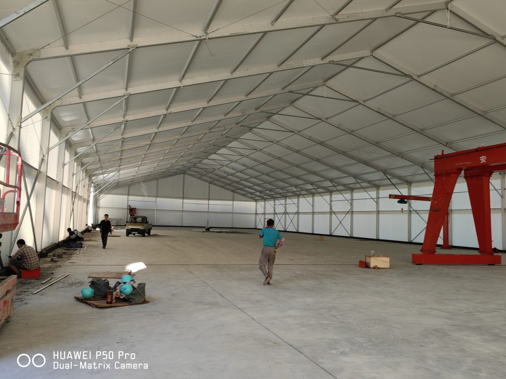 Forklift moving pallets inside a clear span storage tent, no columns, high ceiling for stacking